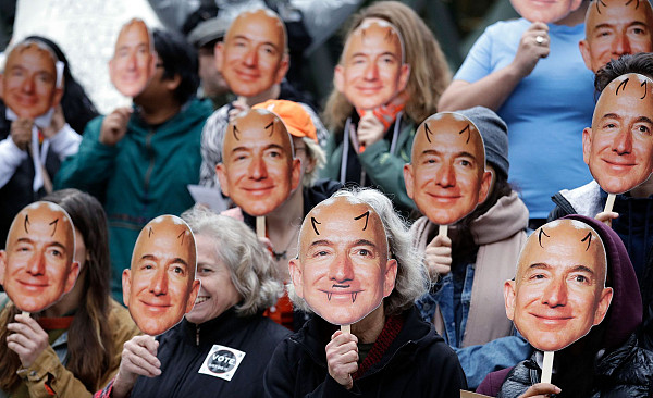 Демонстранты держат маски с изображениями Джеффа Безоса во время акции протеста у штаб-квартиры Amazon в Сиэтле. Они протестуют против системы распознавания лиц Amazon RekognitionAP/Elaine Thompson